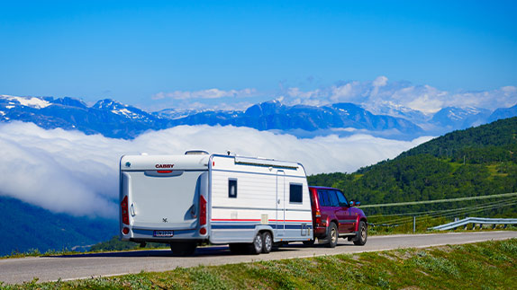 An SUV hauling an RV with a mountain in the background.